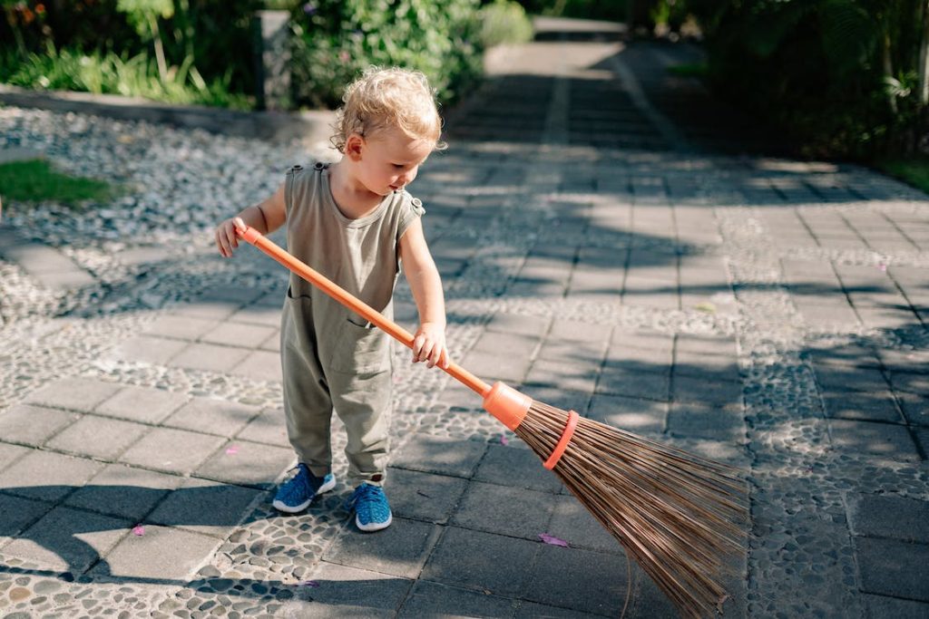 small child sweeping garden